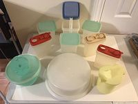 Top view of assorted vintage Tupperware containers of various sizes with lids, including storage containers with pastel colored lids and seals, and mixing bowls.