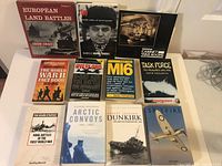 Lot of 11 assorted war-themed books displayed on a white table, titles mostly related to World War II and military history.