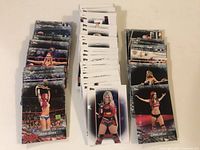 Three stacks of WWE wrestling ladies collectible cards arranged on a beige surface showing the front sides with wrestler images.