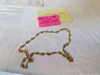 Full view of necklace laid out on fabric with label visible