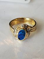 Front perspective showing oval black opal cabochon and diamond accents