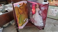 Rapunzel Barbie and 2008 Holiday Barbie dolls in original packaging displayed on small wooden table.