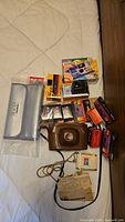 All items in the lot laid out on bed: Black's film pouch, disposable cameras (Fujifilm and Kodak), Kodak Pony 135 camera in case, rolls of film, and film boxes.