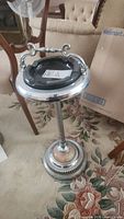 Full view of the metal floor ashtray showing glass insert on top with handle and decorative base