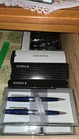 Boxed pens including Bill Blass pen and pencil sets in blue and silver, Parker and Sheaffer pen boxes.