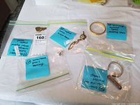 Group view of four labeled bags showing each piece: chain necklace, hinged bracelets, pearl earrings, silver clip cuff