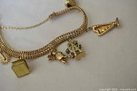 Close-up of multi-strand gold chains with five detailed charms including sunburst, book, cherub, enamel Ferris wheel and Madonna figurine.