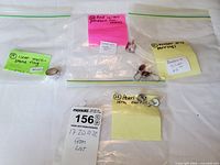 Six pieces of jewelry individually bagged and labeled, including a clear multi-stone ring, pink square pendant with chain, amber drop earrings, and pearl drop earrings.