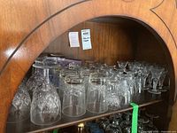 Cabinet shelf showing two plain tumblers at center front, eight inverted diamond‐cut crystal goblets behind left
