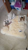 Photo of large lambskin rug and white plush toy bear on carpeted floor.