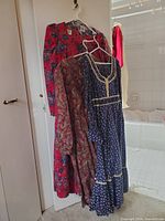Three long floral dresses hanging on a door, showing different color and floral patterns.