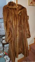 Full-length front view of brown mink fur coat on hanger