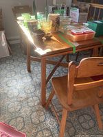 Full view of the rectangular maple dining table with various glassware and small kitchen items on top, showing the light maple wood finish and the attached four chairs around it.