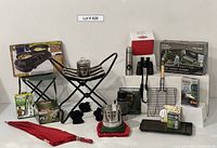 Overview photo showing all camping items including folded stools, umbrella, cooler, pans, grilling tools, boxes, and book.