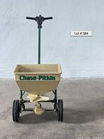 Front view showing the entire Chase-Pitkin spreader including the hopper, wheels, handle, and spreading mechanism.