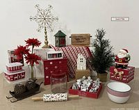 Photo of various Christmas decor items arranged on table including cookie cutters, rolling pin, wooden Advent calendar, small faux plant, and Santa cookie jar box.