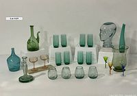 Full lot viewed from front showing all glass pieces including tumblers, candle holders, porron decanter, glass head and colored glassware.
