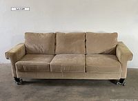 Front view of American Signature light beige fabric sofa showing three seat cushions and caster wheels on legs.