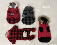 Top-down view showing three dog vests and one dog pajamas laid flat.