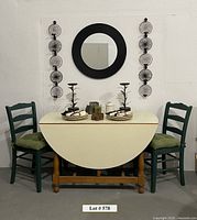 Full set-up showing drop-leaf table with two green chairs, mirror on wall, candle holders, crock and plates with napkins