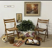 Photo of two wooden folding chairs with autumn-themed home decor arranged between and around them, including pillow with pumpkin design, faux ivy, metal planter, copper mugs, gravy boats, copper ice bucket, tile tray, resin wall art and framed autumn print