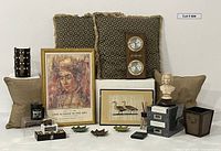 Front view of lot showing chess set, pillows, framed artworks, bust, metal leaves, boxes, candle lantern, shoe shine kit and wallet arranged on floor