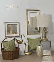 Full lot view showing gold-toned metal swans, green pillows, wicker basket, mirrored cube table, capiz shell vase, wall mirror and framed abstract artwork