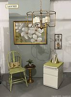 Photo of the home office lot showing green wooden chair with pillow, round metal chandelier with four creamy white shades, white metal filing cabinet with padded green top, small round gold pedestal table with faux plant, framed floral artwork, metal wall sconce candle holder, art deco brass bookends.