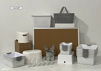 View of all items in the lot showing baskets in different sizes and colors, utensil holder with utensils, step stools, cork bulletin board, and white expandable rack.