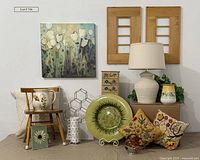 Wide shot of all items in lot showing mugs, display caddy, pitchers, chair, pillows, lamp, sunflowers platter, vase, floral art and frames