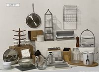 Wide view of all kitchen items arranged on white platforms showing bowls, dish drainer, cookie press, bread box, cutlery block, mug tree, saut pan, peppermill, and others.
