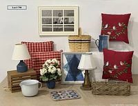 Photo showing all items arranged against a white wall, highlighting pillows, lamps, pitcher, basket, crate, artwork, flowers, and game.