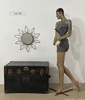 Full view showing the mannequin, large trunk, and metal sunburst mirror on white background.