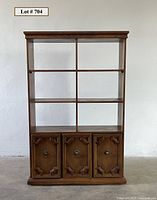 Full front view of the Mediterranean style wooden shelving unit showing open shelves and decorative lower cabinet doors.