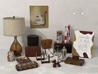 Photo of the entire collection with all listed items arranged together. Shows lamp, artworks, glasses set, cocktail set, balloon dog, boxes, binoculars, portfolio, ashtray, and candle holder.