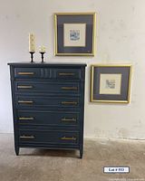 Full front view of navy dresser, two framed artworks on wall, and two candle holders on top