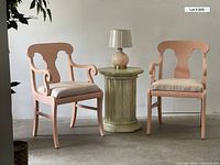 Photo showing pair of peach neoclassical chairs with beige seats, octagonal side table in green finish, and matching peach lamp with beige shade centered on table.
