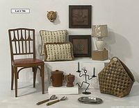 Full lot view showing wood carved cheetah mask, framed wood carved leaves, woven basket, wooden chair, lamp, pillows, and kitchen items arranged on white platforms.