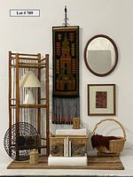 Full view of bamboo shelving unit with lamp, kilim wall hanging, mirror, framed artwork, baskets, bookends, and decorative items arranged beneath the hanging