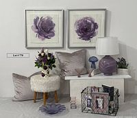 Photo of entire lot showing framed artworks on wall, lamp, pillows, stool, glass mushroom, martini glasses, faux plant, bowl, vase, pitcher with flowers, wire basket, and aromatherapy kit arranged on floor and small bench.