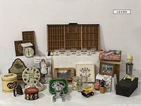 Full view of all assorted vintage and antique items arranged, showing tins, presses, glasses, artwork, fire alarm, and kitchen scale