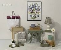 Front view of framed whimsical floral poster with assorted home decor arranged below including iron stool, plant pots, metal horse statue, white lamp, and baskets.