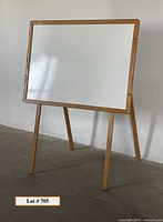 Full view of the whiteboard easel showing wooden legs and frame, standing upright on the floor.