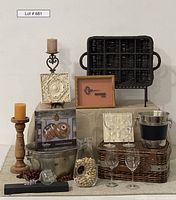 Full lot view showing all items including wicker wine crate, candlesticks, framed key, relief carvings, picnic basket, and glassware