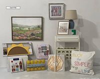 Collection items arranged on a flat surface with framed artwork above, showing all decorative elements including table, pillows, art kits and lanterns.
