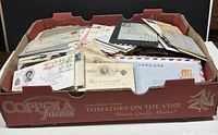 Box filled with vintage covers and first day covers in assorted sizes and conditions, arranged loosely with visible stamps and postmarks.