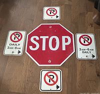 Full view of 5 vintage traffic signs including 1 octagonal STOP sign and 4 rectangular No Parking signs with arrows and time restrictions.