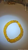 Photo of a golden-yellow Baltic amber beaded bracelet, showing translucent polished beads with a uniform size and rounded shape.