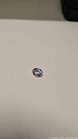 Close-up photo of a light blue oval cut natural aquamarine gemstone on a light surface.