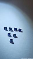 Seven natural blue sapphire stones photo showing their deep blue color and princess cut shape.